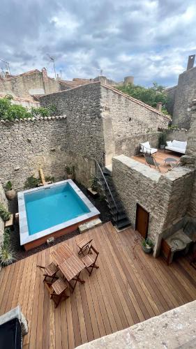 - une piscine sur une terrasse en bois à côté d'un bâtiment dans l'établissement La Maison du Puits B&B Minervois, à Cesseras