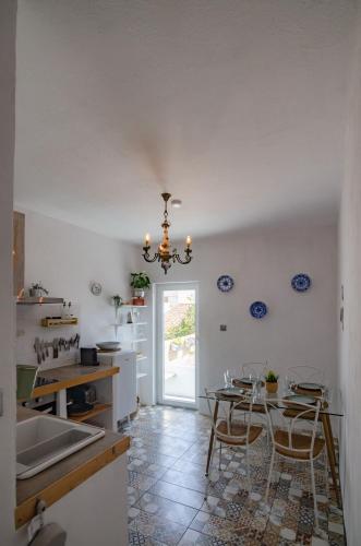 a kitchen with a table and chairs and a chandelier at Little Bispo Apartments in Vila do Bispo