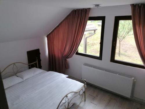 sypialnia z białym łóżkiem i 2 oknami w obiekcie CasAndi w mieście Cireşu