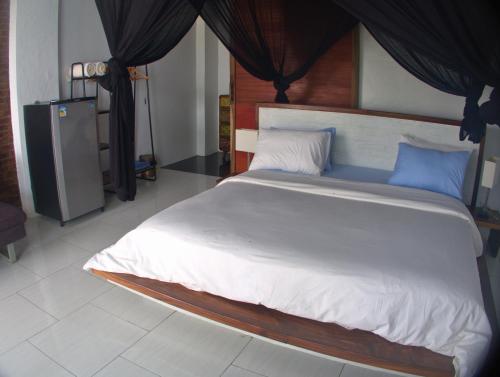 a bedroom with a large white bed with blue pillows at 3 Waves Hotel in Huu