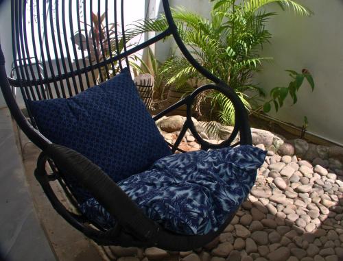 a black rocking chair with a blue pillow in a garden at 3 Waves Hotel in Huu
