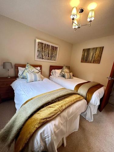 a bedroom with two beds with white sheets at Gleneagles Lettings in Auchterarder