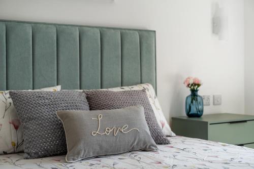 a bed with a pillow with the word love on it at Newly Refurbished 2 Bed Flat in Mill Hill