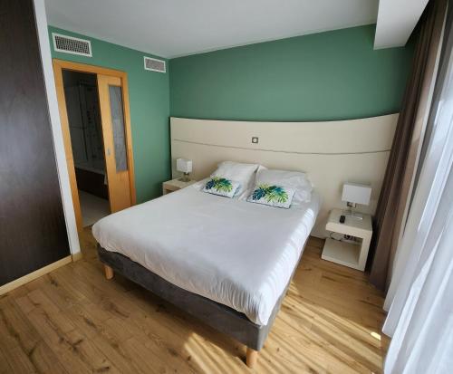 een slaapkamer met een bed met 2 kussens erop bij Hôtel Montaigne & Spa in Cannes