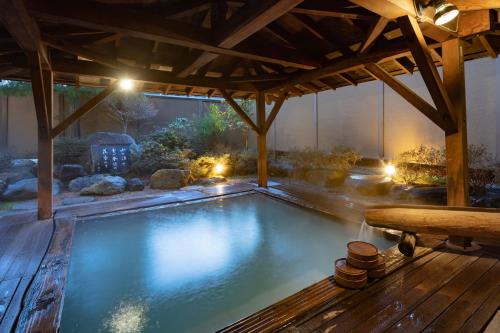 a swimming pool under a pavilion with a wooden deck at Azumakan in Nihommatsu