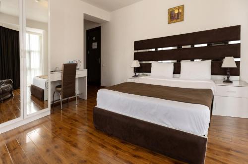 a bedroom with a large bed and a desk at Hotel Grand Palace in Tbilisi City