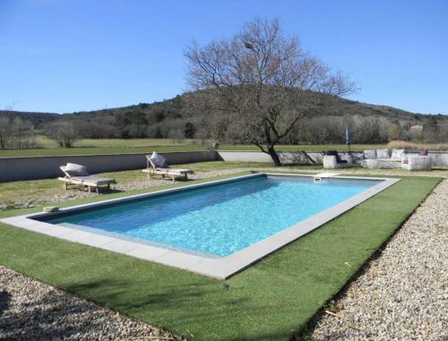 een zwembad op het gras met twee banken eromheen bij La Grange de Marie in Valaurie