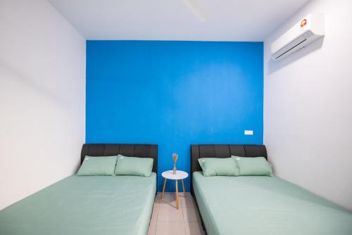 2 camas en una habitación con una pared azul en No 19 Studio Homestay (Semi-D), Port Dickson (up to 13 pax) en Port Dickson