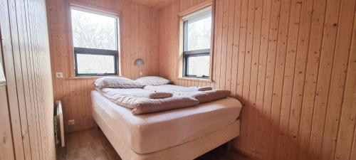 a small bed in a room with two windows at Kirkjubraut - Church street in Talknafjordur