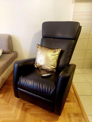 a black leather chair with a gold pillow on it at Apartman Teo in Lukavica