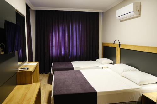 1 dormitorio con 2 camas y cortina púrpura en Club Wasa Holiday Village All Inclusive, en Toslak