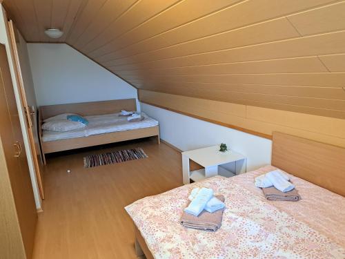 een kleine zolderslaapkamer met 2 bedden en handdoeken erop bij Getaway "At the three lights" in Sevnica