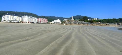 uma praia vazia com edifícios ao fundo em Alojamientos Viveiro - Ático Playa de Covas em Viveiro