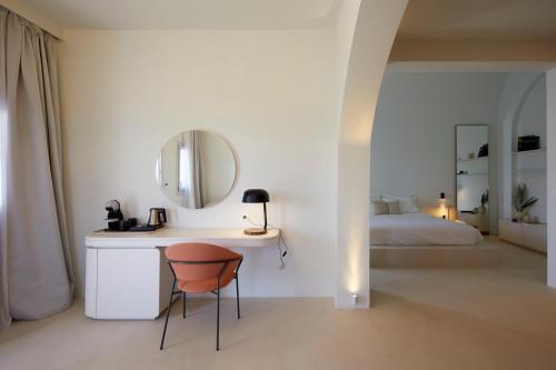 a bedroom with a bed and a desk with a mirror at Orabel Suites Santorini (Adults Only) in Perivolos