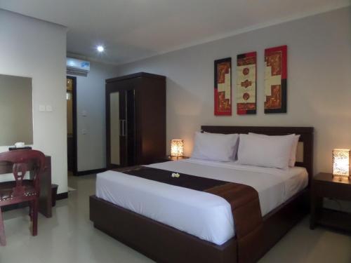 a bedroom with a large white bed and a desk at Mansu Hotel and Spa Legian in Kuta