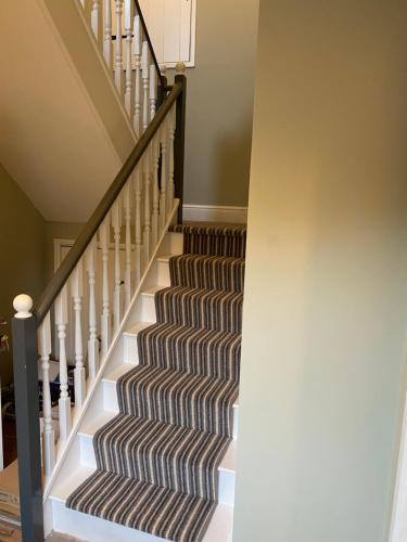 a staircase in a home with a striped rug at Black Mountain Lodge in Glasbury