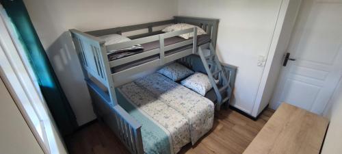 a bunk bed in a room with a bed and a chair at Le Bord Chêne in Salazie