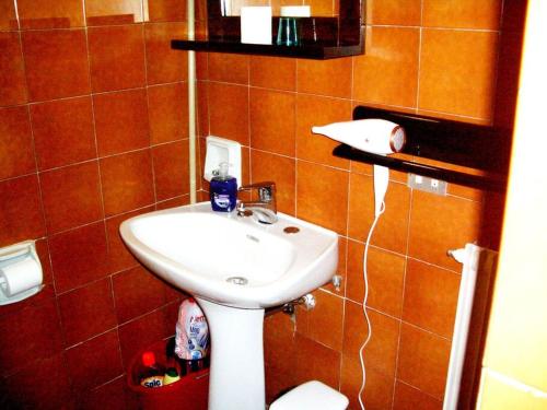 ein Badezimmer mit einem weißen Waschbecken in einer braun gefliesten Wand in der Unterkunft Villa (apartment F) — Pool — Lake Idro in Vesta