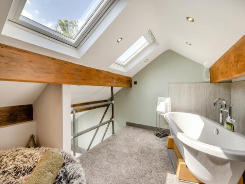 a bathroom with a skylight and a tub and a sink at Squirrel Cottage in Glossop