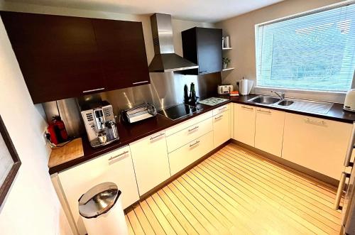a kitchen with white cabinets and a wooden floor at Gleneagles Lettings in Auchterarder