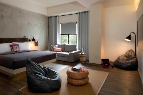 a bedroom with a bed and a living room at MOXY Bandung in Bandung