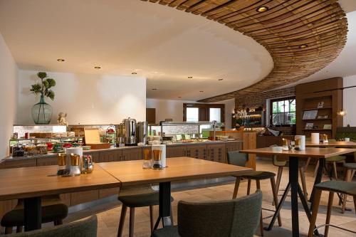 um restaurante com mesas e cadeiras de madeira e uma cozinha em Weingut Ferdl Denk em Weissenkirchen in der Wachau