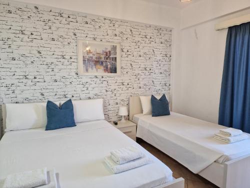 2 Betten in einem Zimmer mit Ziegelwand in der Unterkunft Villa White in Ksamil