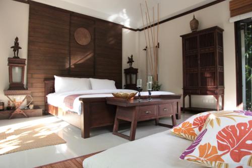 um quarto com uma cama e uma cabeceira em madeira em KhgeMa NuanJun Pool Villa Gallery Resort em Ban Huai Yai