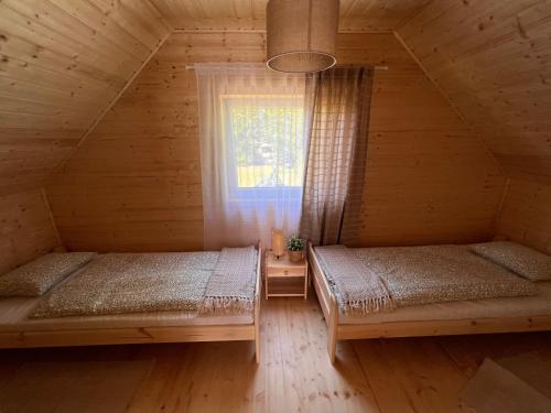 dwa łóżka w drewnianym domku z oknem w obiekcie Leśny Zakątek w mieście Lubiatowo