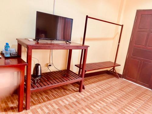 einen Holztisch mit einem TV darüber in der Unterkunft Hana Riverside Hotel in Vang Vieng