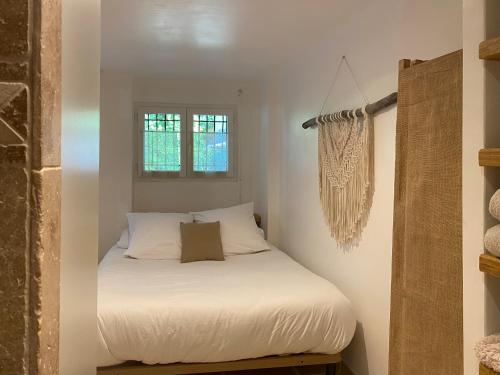 Cette petite chambre comprend un lit avec des draps blancs. dans l'établissement Les Sources, à Fontaine-de-Vaucluse