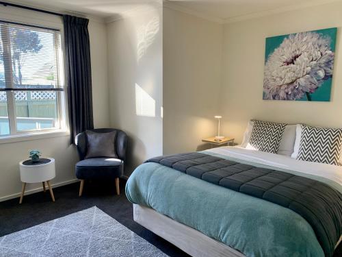 1 dormitorio con 1 cama, 1 silla y 1 ventana en March Apartments en Dunedin