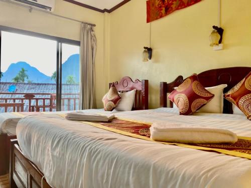 two beds in a room with a large window at Hana Riverside Hotel in Vang Vieng