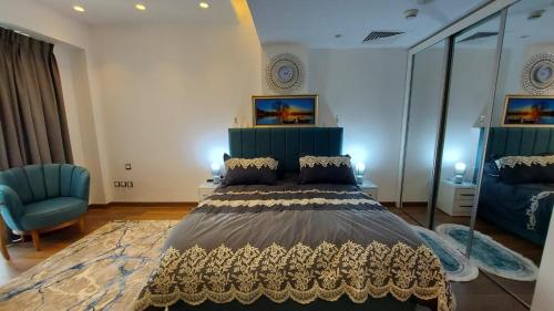 a bedroom with a large bed and a blue chair at Furnished apartment in Damac Tower. Jordan in Amman