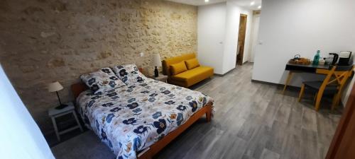 a bedroom with a bed and a yellow chair at La petite ferme 37 in Épeigné-les-Bois