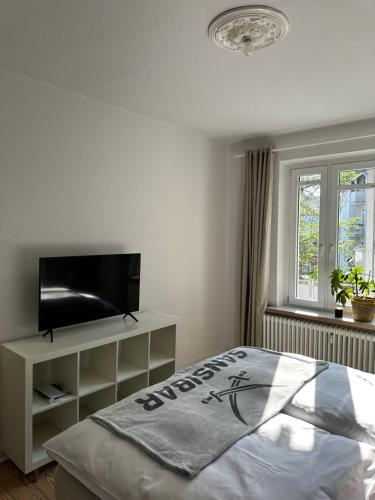 Schlafzimmer mit einem Flachbild-TV und einem Bett in der Unterkunft Großzügige 3-Zimmer Altbauwohnung in Kiel