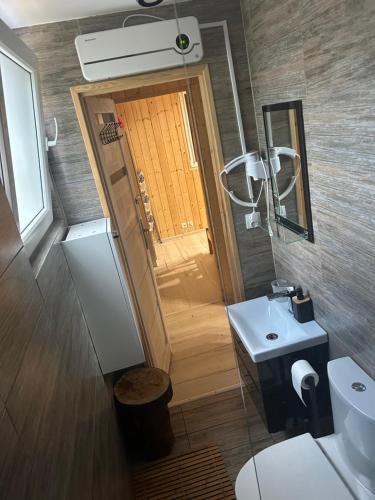 a bathroom with a toilet and a sink and a door at Domek Wakacyjny Maciuś 48 in Głębokie