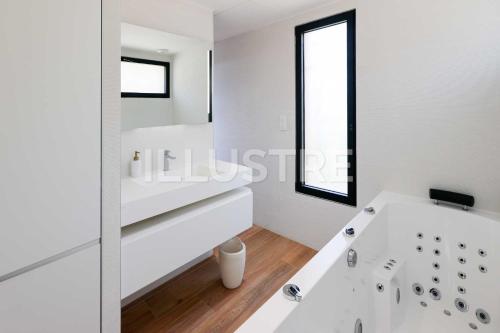 a white bathroom with a tub and a window at Villa Vue Mer, Piscine & Plage à 6Min in Cagnes-sur-Mer
