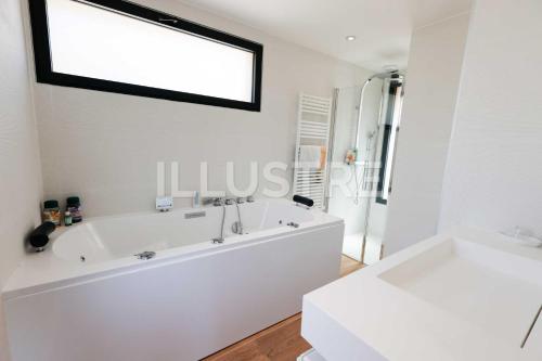 een witte badkamer met een bad en een douche bij Villa Vue Mer, Piscine Chauffée & Plage à 6Min in Cagnes-sur-Mer