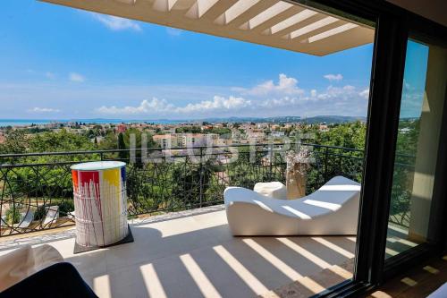 a balcony with a chair and a view of a city at Villa Vue Mer, Piscine & Plage à 6Min in Cagnes-sur-Mer