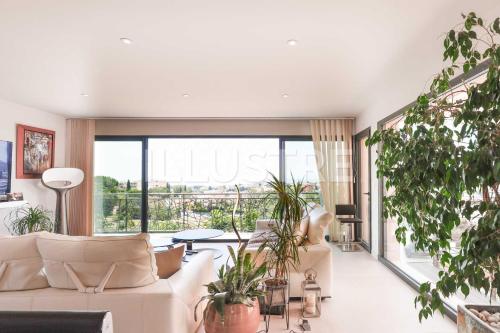 a living room with a white couch and some plants at Villa Vue Mer, Piscine & Plage à 6Min in Cagnes-sur-Mer