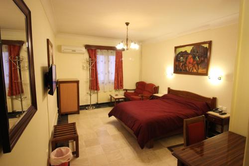 1 dormitorio con 1 cama roja y 1 silla en Hotel Hydra en Argel
