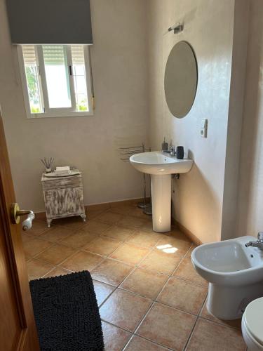 a bathroom with a sink and a toilet and a mirror at Habitación con baño Malva in Lepe