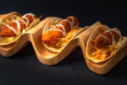 a group of three hot dogs on a wooden tray at Shepherd Hotel in Amman