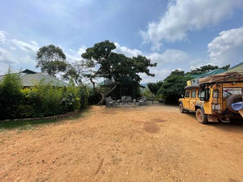 a yellow bus parked on a dirt road at Bwindi My Home in Kachulagenyi