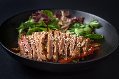 a black bowl of food with meat and vegetables at Shepherd Hotel in Amman