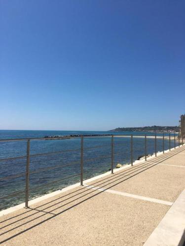 a sidewalk next to the ocean with a fence at Mare Azzurro Appartamento in Sciacca