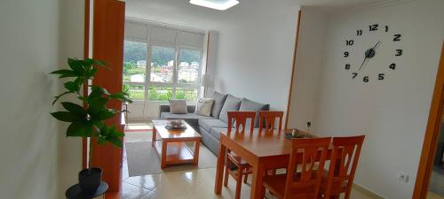 sala de estar con mesa y reloj en la pared en Alojamientos Viveiro - Playa de Covas II en Viveiro