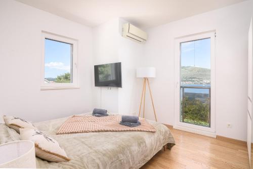 a white bedroom with a bed and two windows at L&L Luxury apartment 1 in Okrug Donji