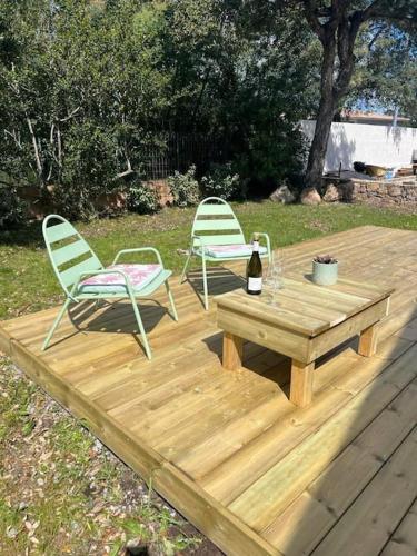 a wooden deck with two chairs and a table and a bottle of wine at Appartement les pieds dans l'eau in Solaro